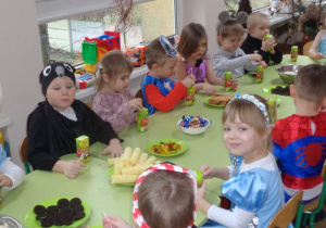 Dzieci jedzą poczęstunek w trakcie balu karnawałowego